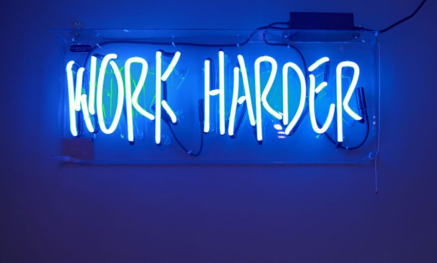Der Begriff "work harder" in blauer Leuchtschrift